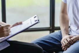 A man sits opposite a nurse.