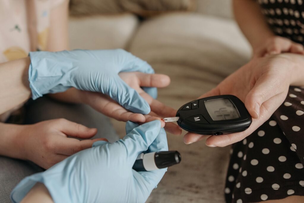 several hands carrying out a blood glucose test on a patients finger. 